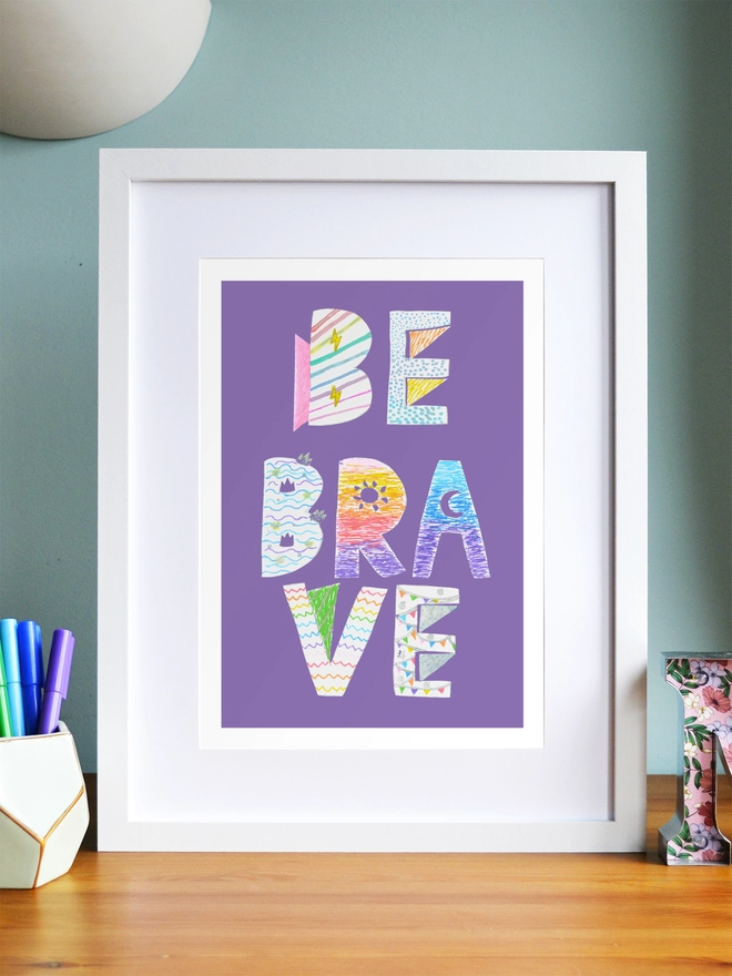 Art print saying 'Be brave' in a white frame in a child's room