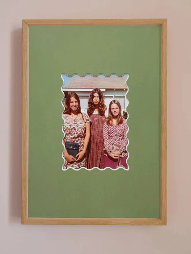 Ric rac photo mount frame with a green mount featuring a decorative ric rac boarder around a centered Instax photo, displayed on a neutral beige wall.