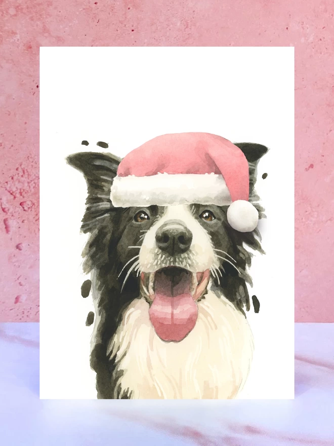 A Christmas card featuring a hand painted design of a border collie, stood upright on a marble surface surrounded by pompoms. 