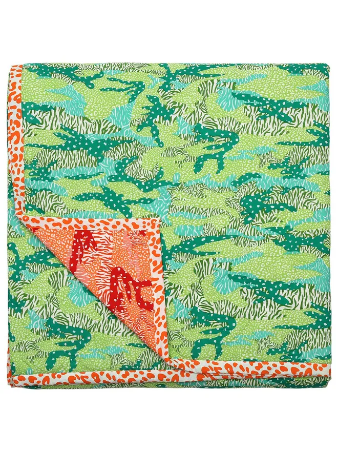 Big Cat Camo quilt, reversible orange and green camouflage and animal print quilt folded on a white background.