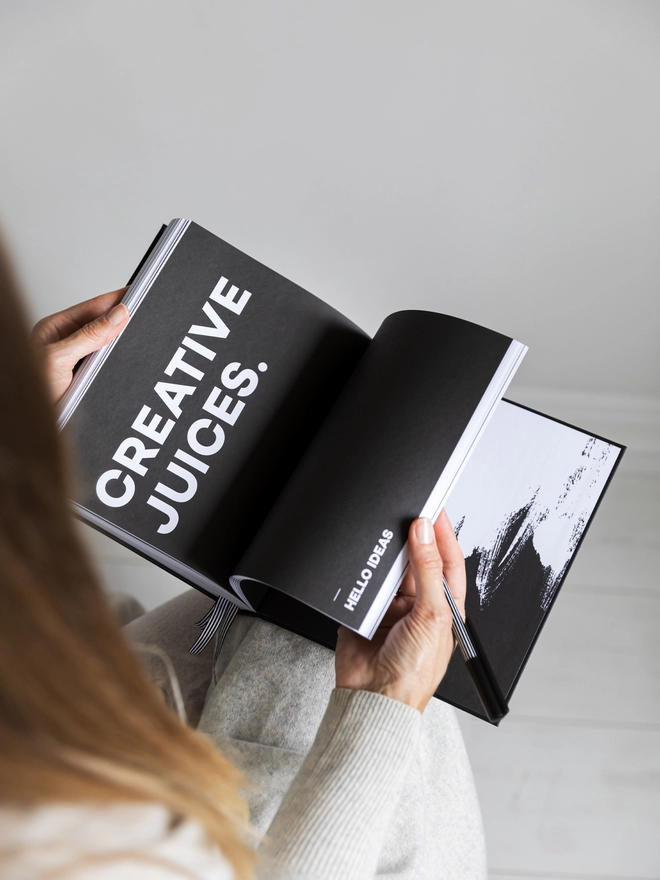 Lady flicking through planner looking at a black and white quote page reading 'Creative Juices'.