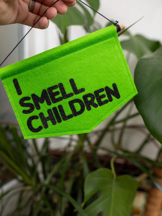 Green, fell halloween banner that has "I SMEEL CHILDREN" written on it in black glitter felt.