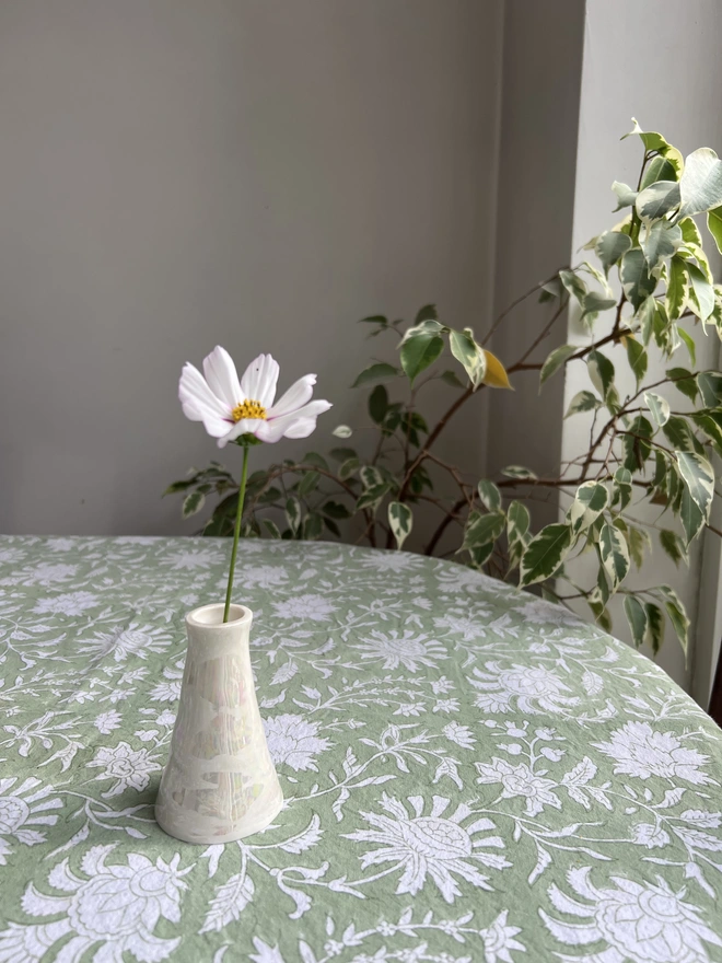 handmade pearl lustre porcelain bud vase with cosmos on block printed tablecloth