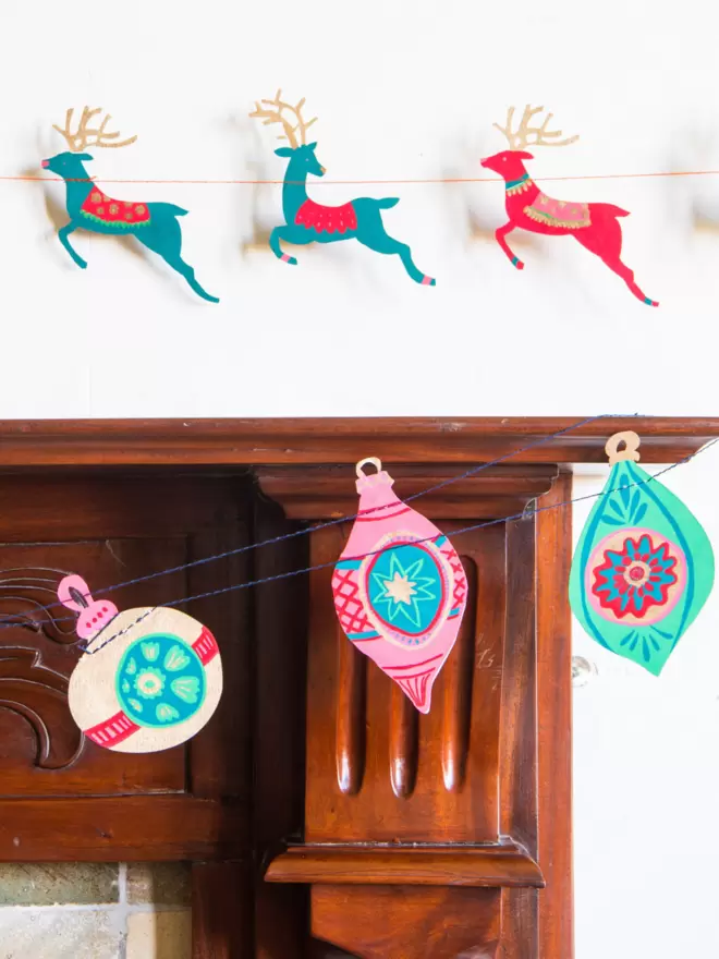 Garland hanging along the fireplace with the colourful reindeer garland in the back