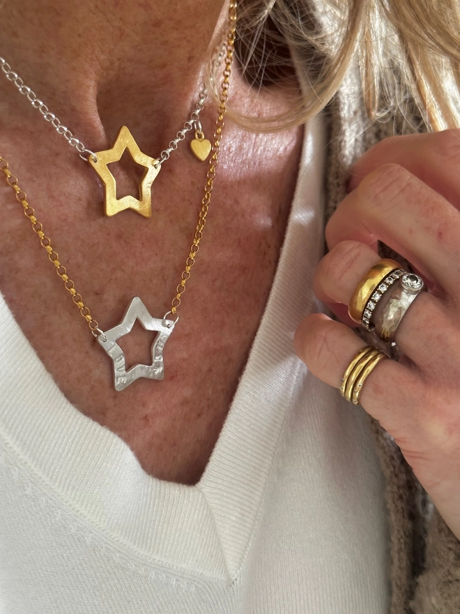 model wears sterling silver chain with gold open star charm and gold mini heart charm, and gold chain with personalised silver open star charm