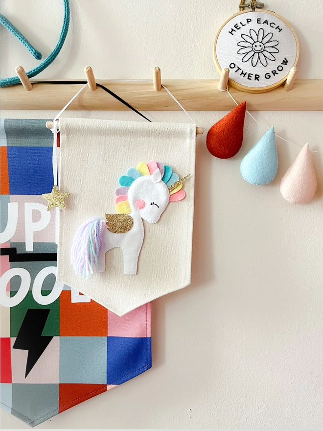 White and pastel unicorn banner hanging on a wooden peg rail