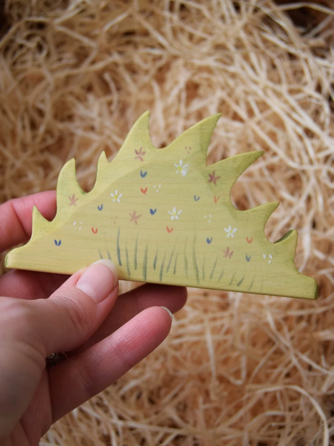 wooden toy flower patch held in hand over woodwool