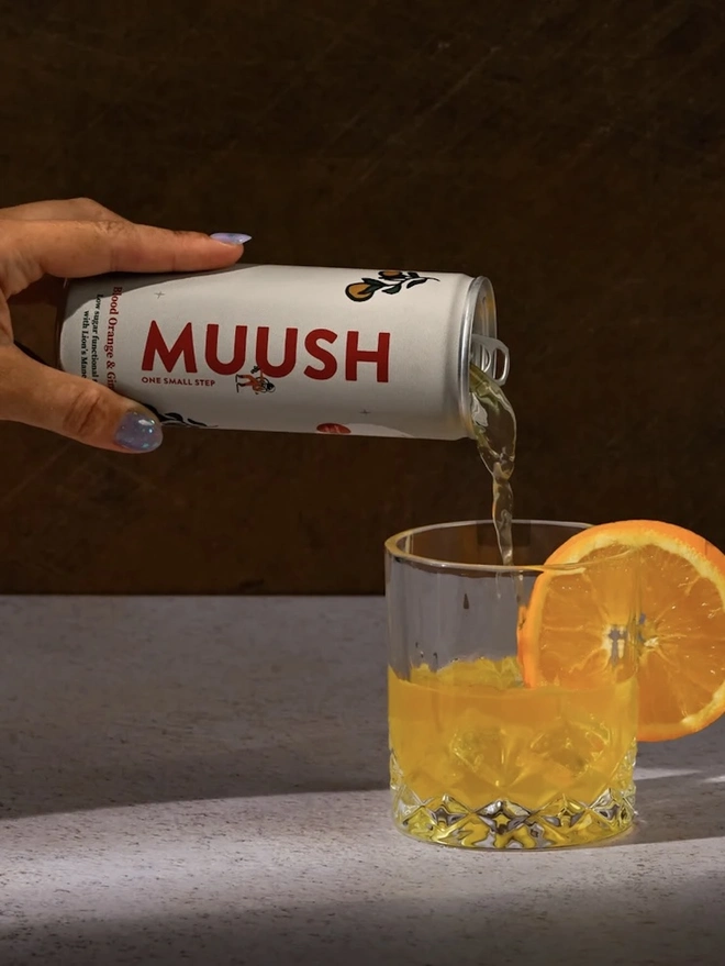 Blood Orange & Ginger Cans (Pack Of 12), an image of a soda being poured into a glass by a person. 