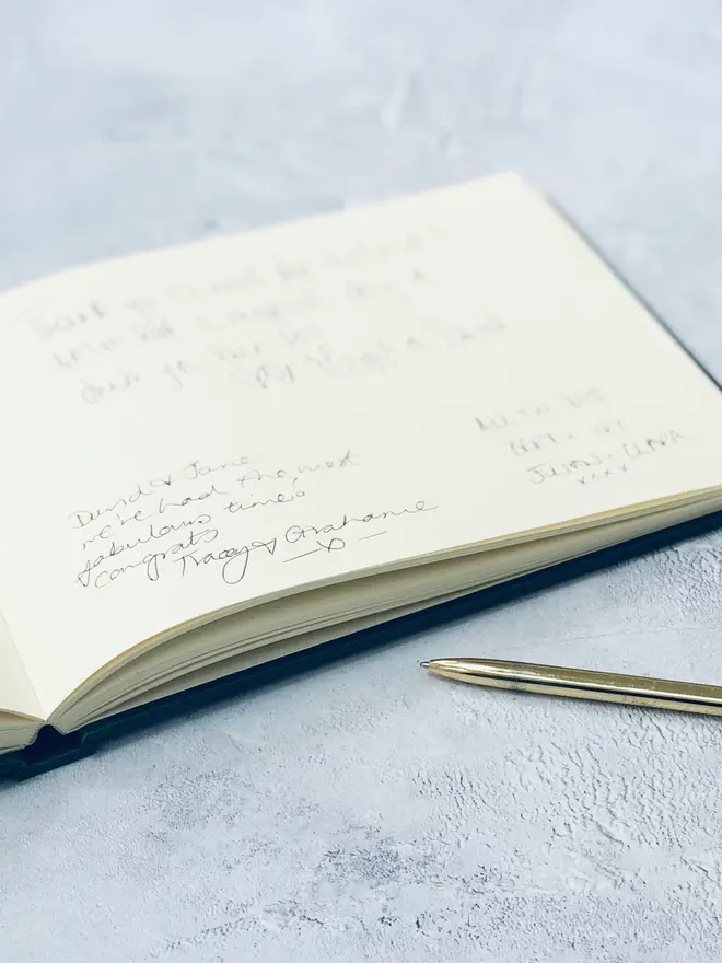 Personalised Calligraphy Font Wedding Guest Book, opened on marble surface. 