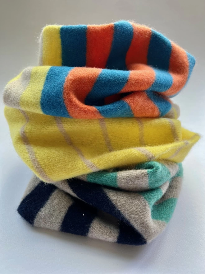 Different coloured knitted snoods shown stacked onto of each other