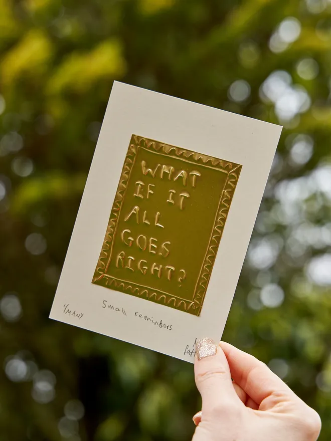 What if it all goes right - tin embossing on white card, in front of a leafy background, held by a female hand
