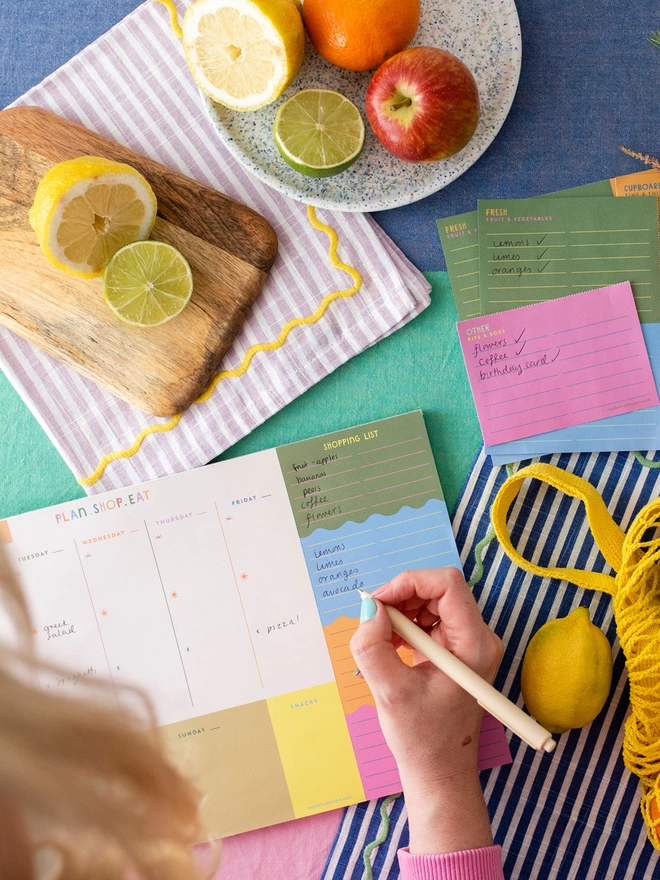 Writing a food shopping list on Raspberry Blossom tear off weekly food planner