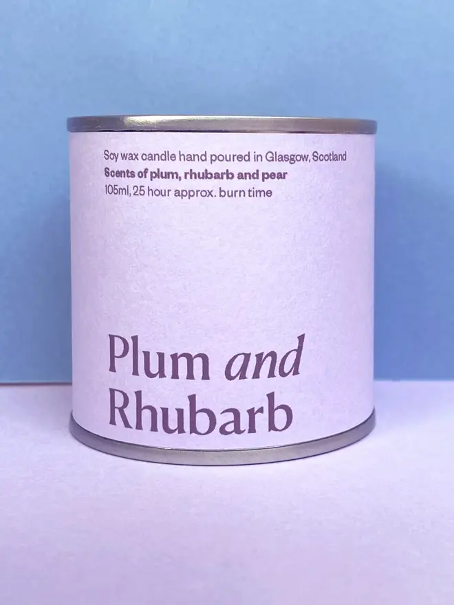 lum & Rhubarb Soy Wax Candle Tin, against a purple and blue background. 