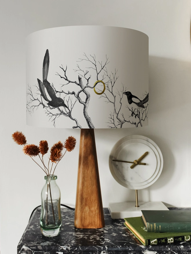 Handmade lampshade featuring cheeky magpies with gleaming gold details, inspired by traditional folklore and whimsical home decor.