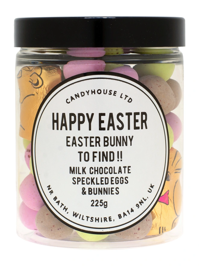 A clear Jar with a black lid filled with speckled eggs and a chocolate easter bunny inside
