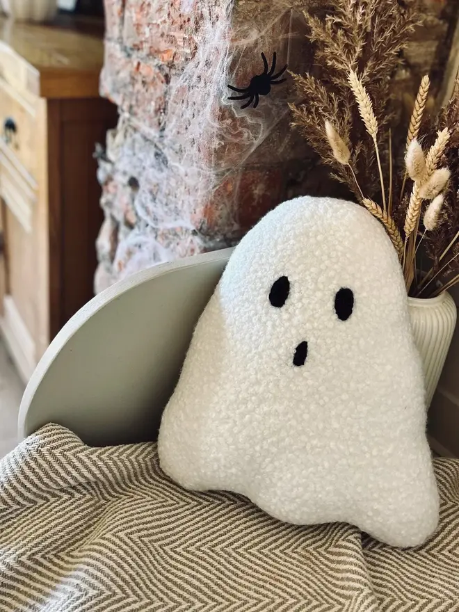 boucle ghost pillow. a white cushion in the shape of a ghost.