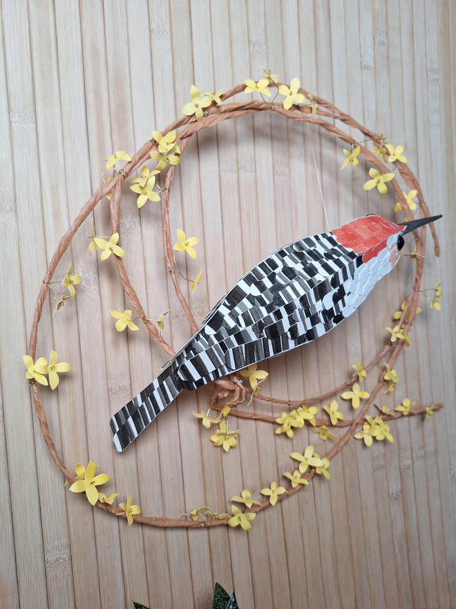 Back side view of a forsythia wreath featuring a woodpecker sculpture