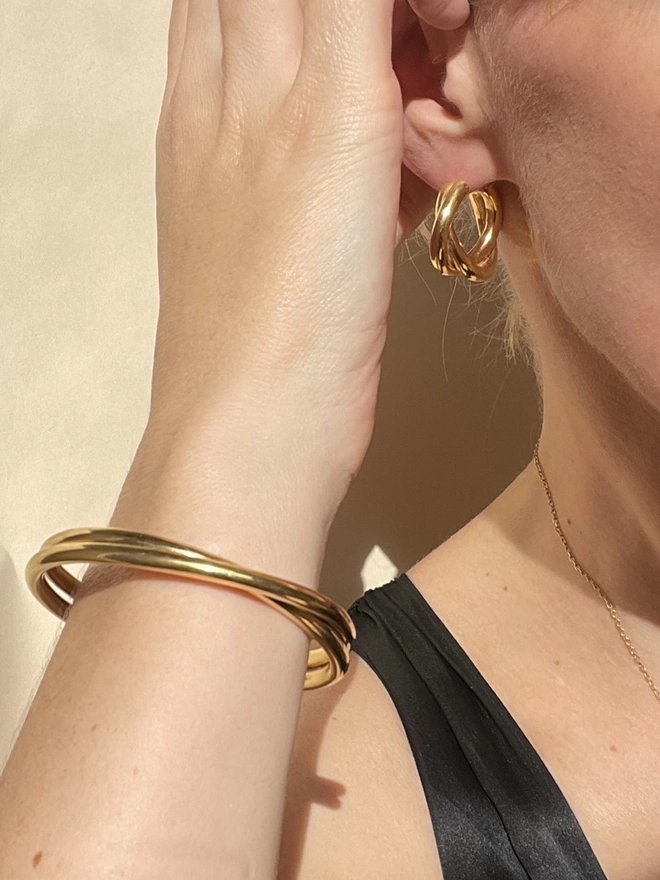 twisted 18 carat cuff worn with matching gold hoop earrings