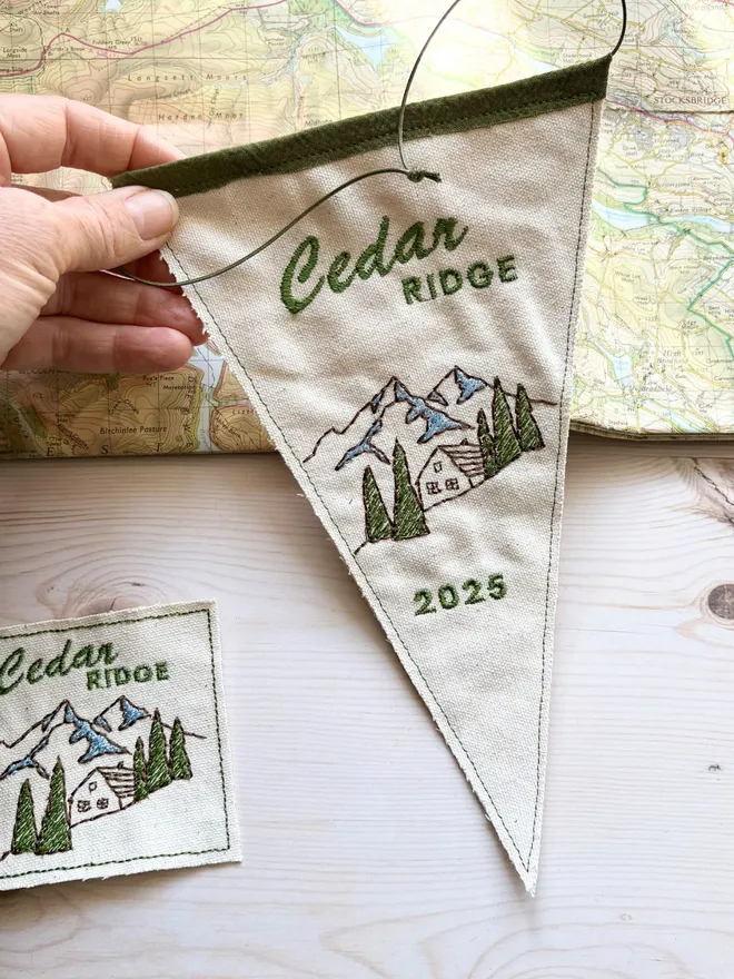 A mini embroidered cabin location pennant flag on a vintage map