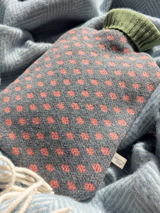 COLOURFUL HOT WATER BOTTLE COVER DISPLAYED ON A ON A BLANKET