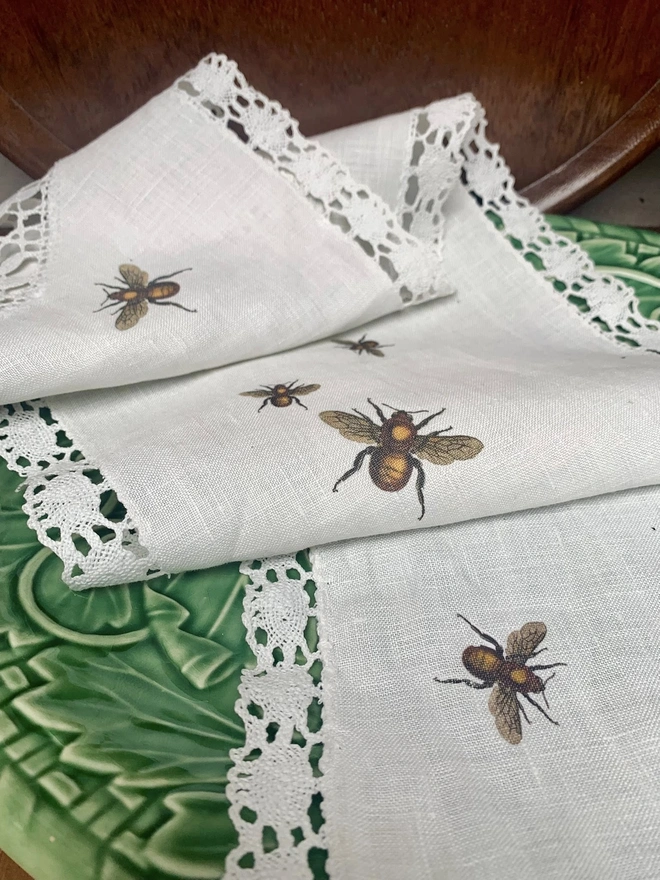 A folded linen and lace table runner on a green majolica platter