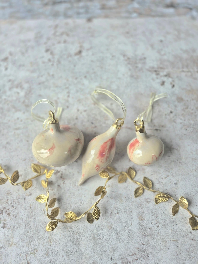 Ceramic christmas bauble decorations in a pearlescent glaze with white, cream and pink and gold, with silk ribbon and gold detailing. Photographed on a pearlescent serving dish with gold pears and christmas lights, gift, christmas, ceramics, pottery, christmas, decorations, christmas tree