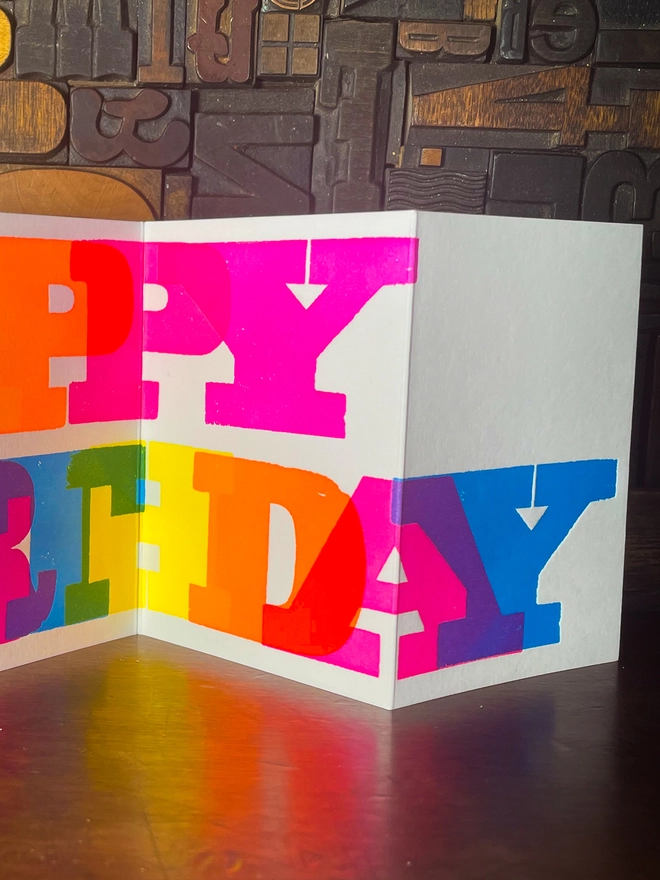 Artisan letterpress printed "Happy Birthday" concertina card featuring bold typography in six fluorescent inks with a deep impression print