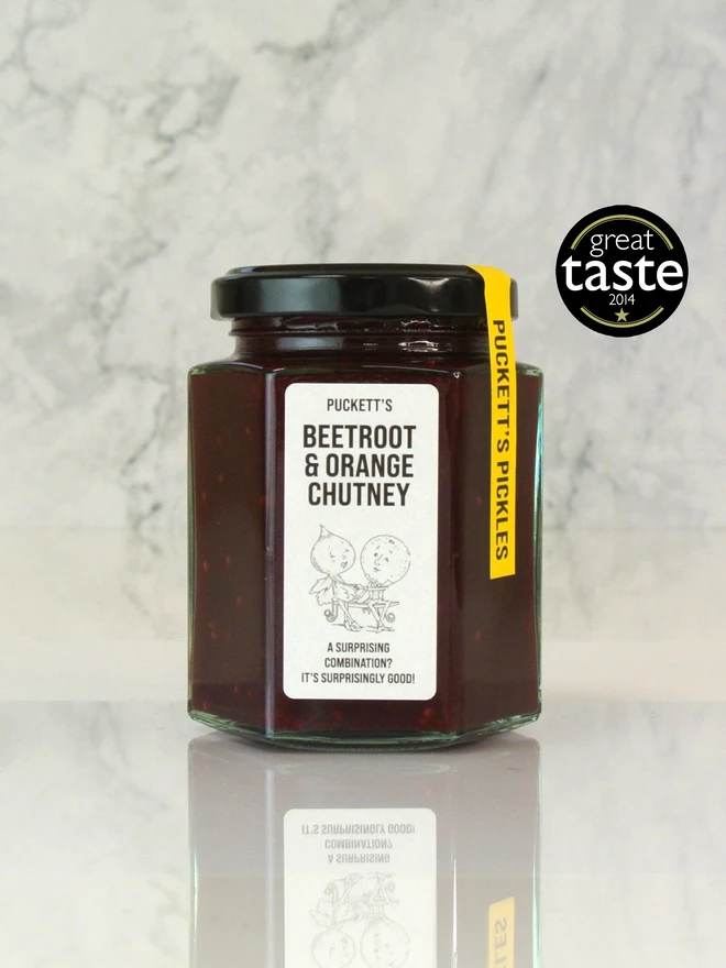 beetroot and orange chutney. a jar of chutney photographed against a marble background.