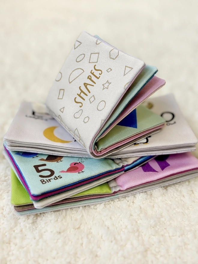 The 4 little softs books included in the little library book set laying on a rug and open one on top of the other and the one