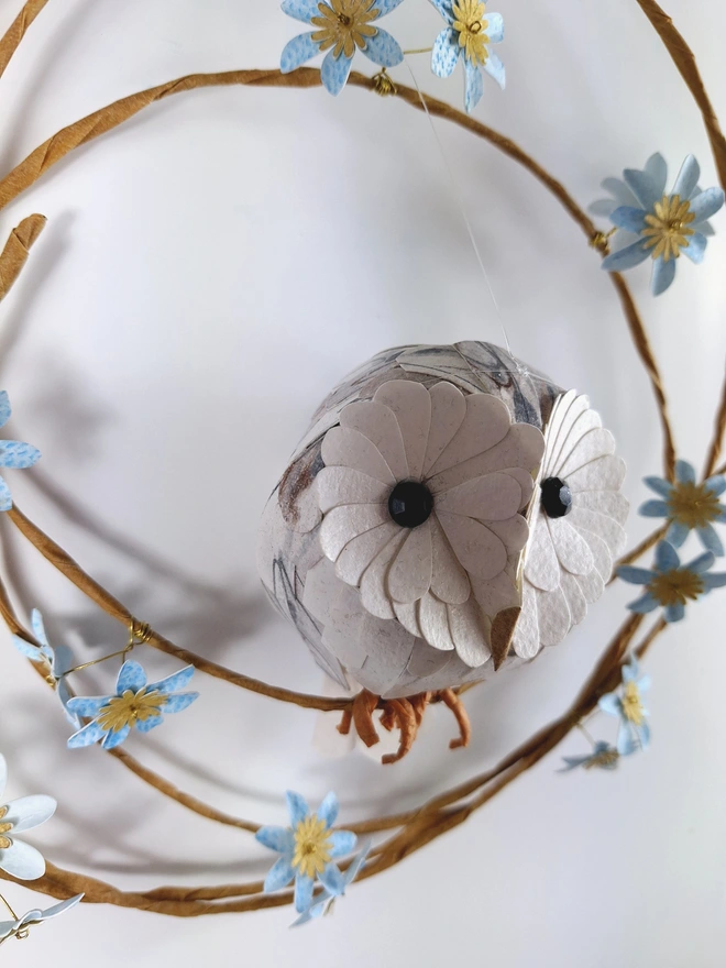 close up of handmade wall art depicting a baby barn owl on a wreath of blue flowers