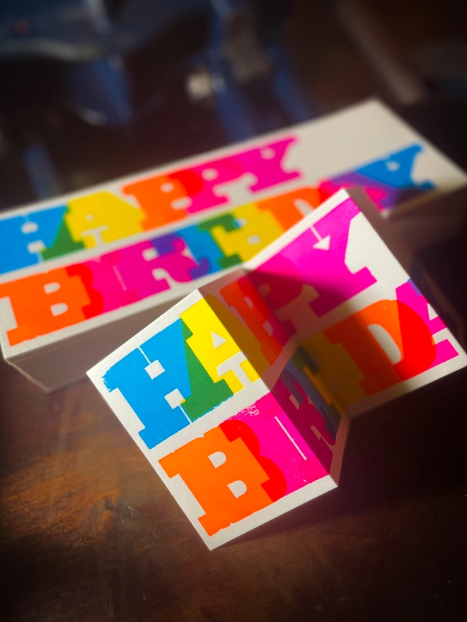 Artisan letterpress printed "Happy Birthday" concertina card featuring bold typography in six fluorescent inks with a deep impression print