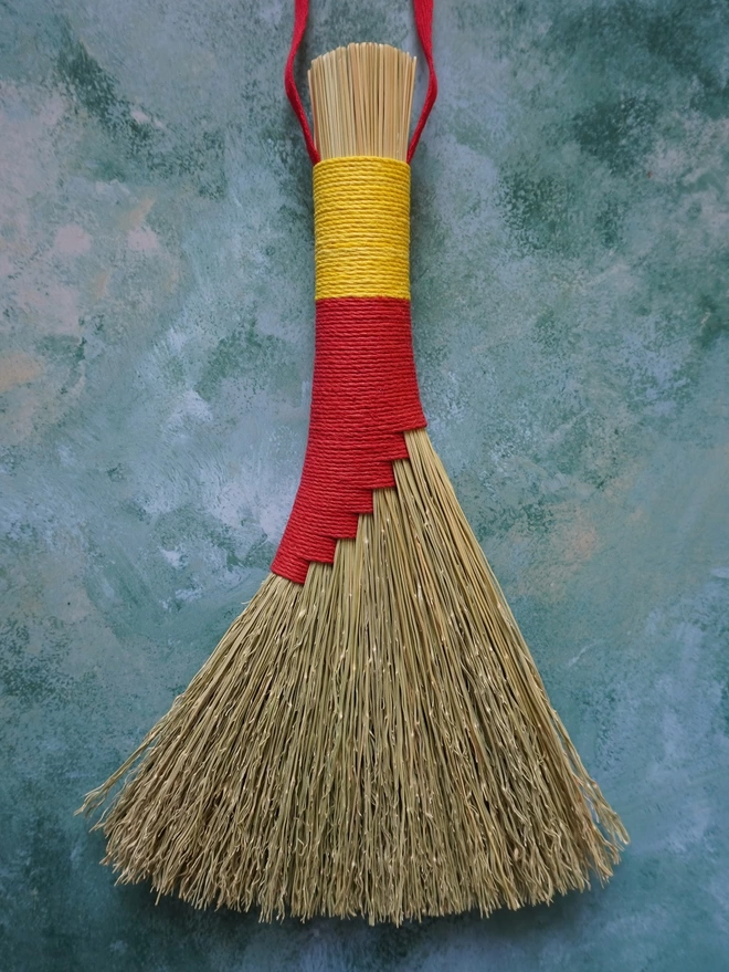 Handmade broomcorn brush with red and yellow hemp cord binding