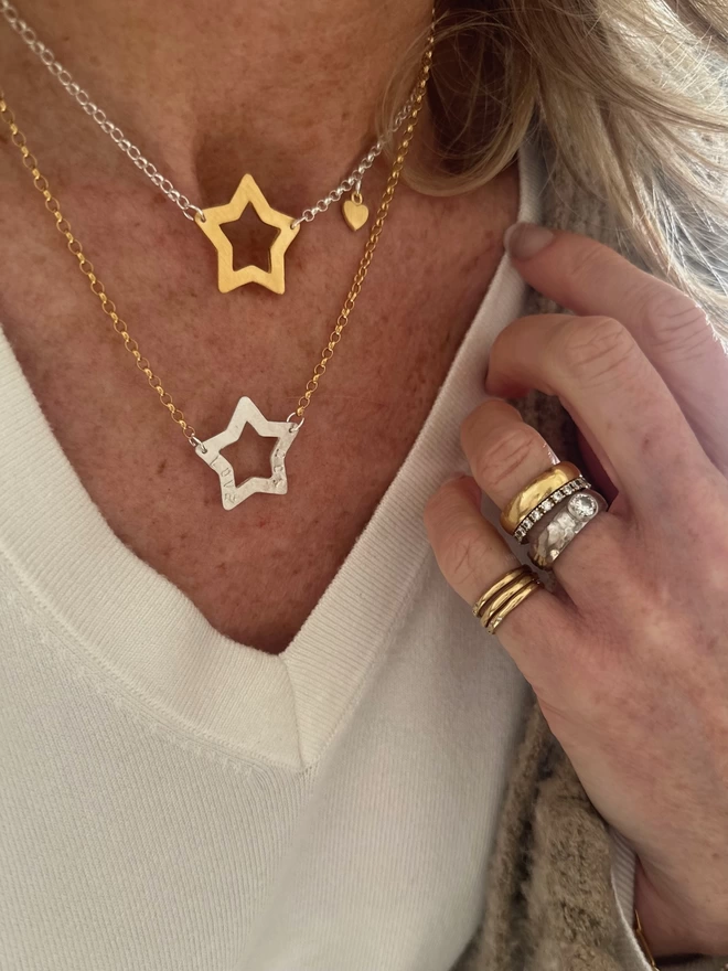 model wears sterling silver chain with gold open star charm and gold mini heart charm, and gold chain with personalised silver open star charm
