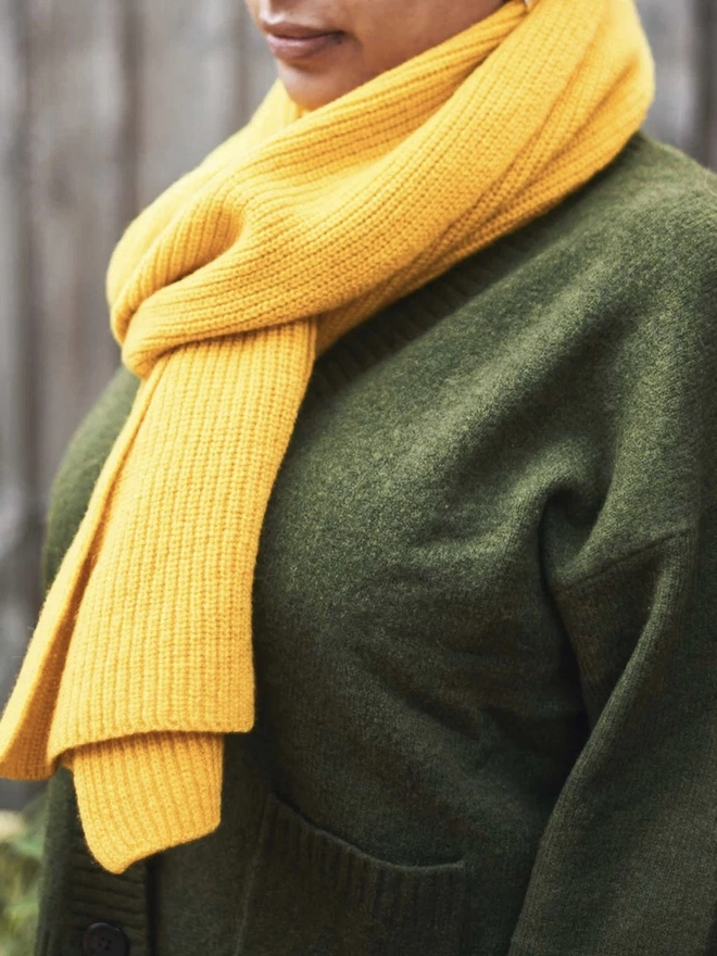 Lambswool Ribbed Scarf, a woman wearing a colourful ribbed scarf outdoors. 