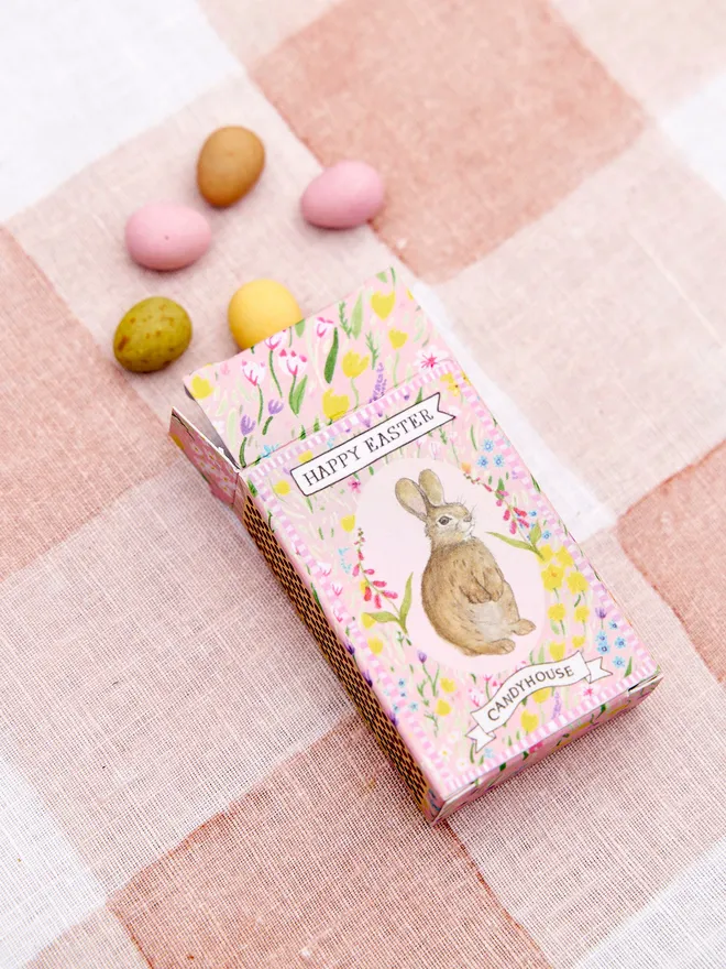 A pink box of Easter speckled eggs on a pink and white tablecloth