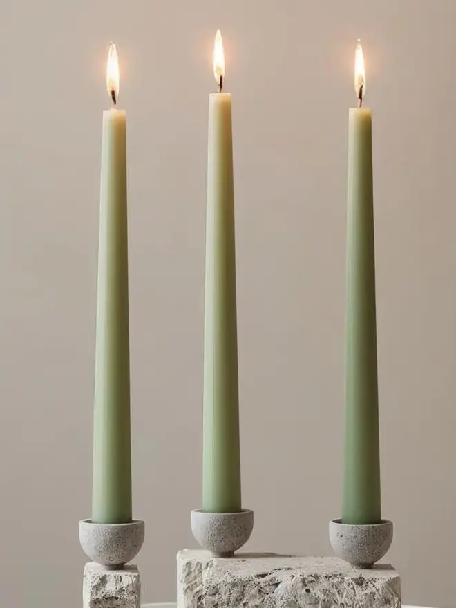 Sage green three dinner candles in holders
