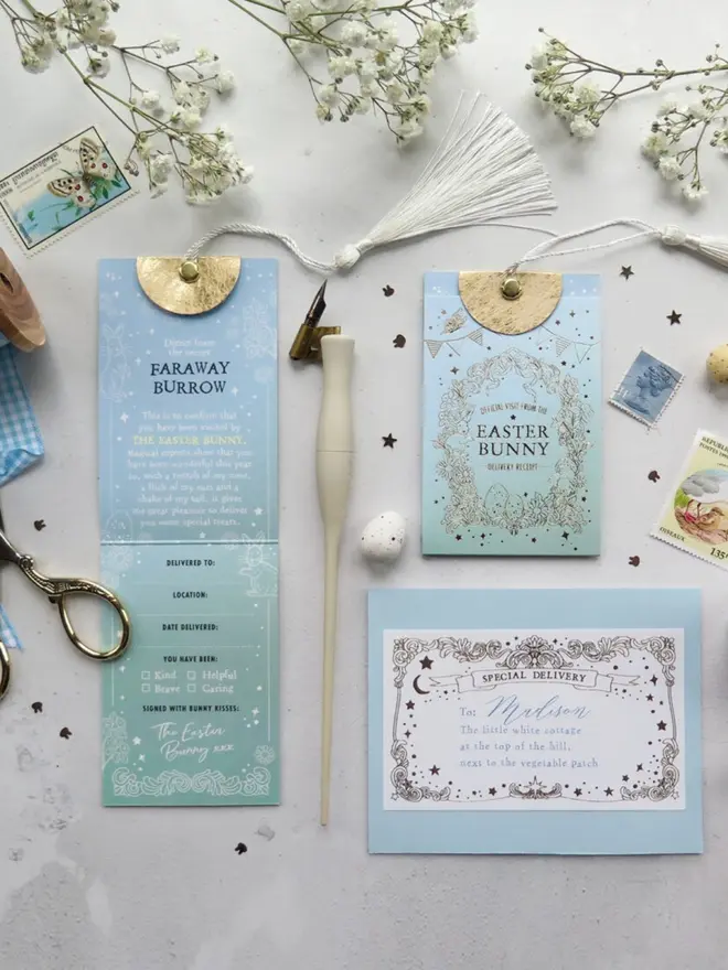 The full set from above: the opened Faraway Burrow treats card, the gold foil pouch and Madison's addressed envelope. Vintage stamps, a white tassel and gold scissors surround them.