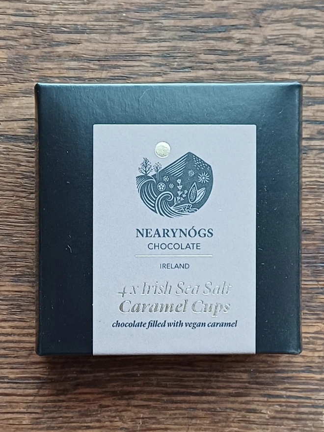 Vegan Irish Sea Salt Chocolate Caramel Cups 60% (Box Of 4), a box of chocolate cups sitting on a wooden surface. 