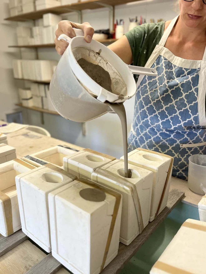 In her studio Katie is filling plaster moulds with slip (liquid clay) from a large plastic jug.