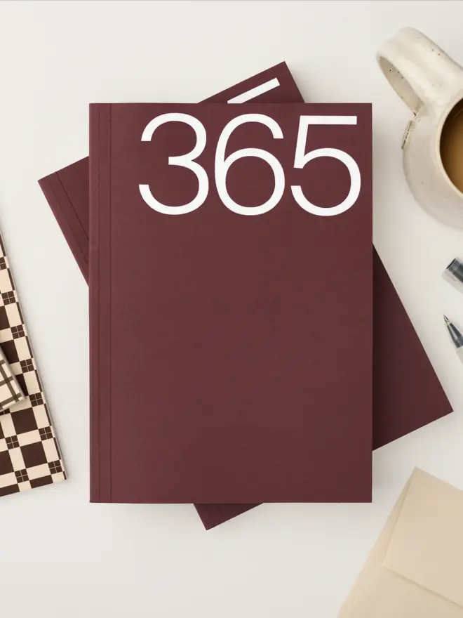 Claret coloured softcover, smooth untextured cover stock. Foiled with a white 365. A5 in size