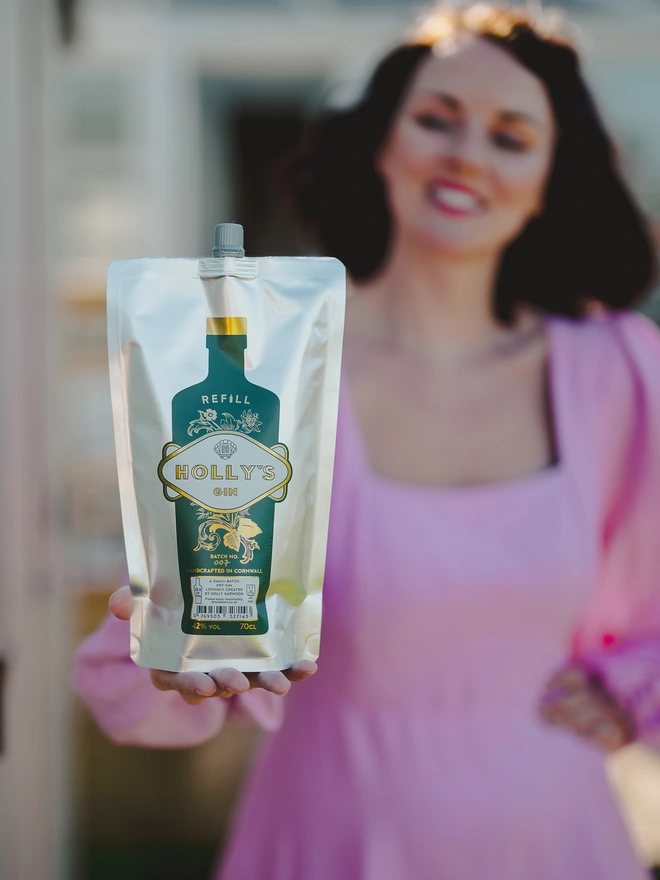 Holly, smiling and holding gin refill pouch