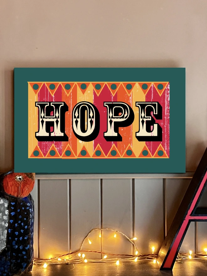 colourful hand painted Hope sign in fairground lettering with orange pink and yellow stripes, with orange and yellow zig zag patterns  top and bottom