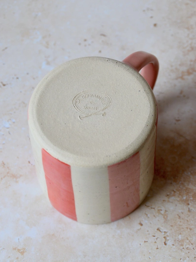 Bonbon Mug — base view showing red and pink striped design with maker’s mark
