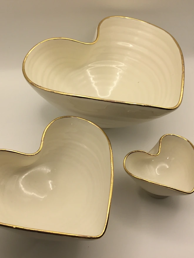 porcelain heart shaped bowl. three white heart shaped bowls with gold rims, in three different sizes.