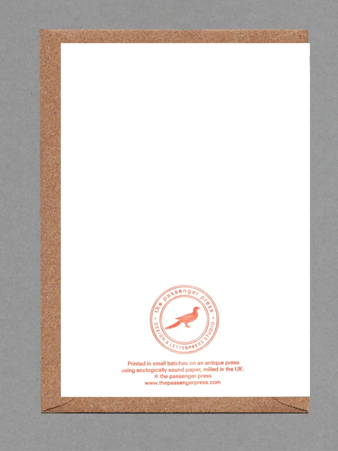 Back of white card with orange text and brown envelope behind