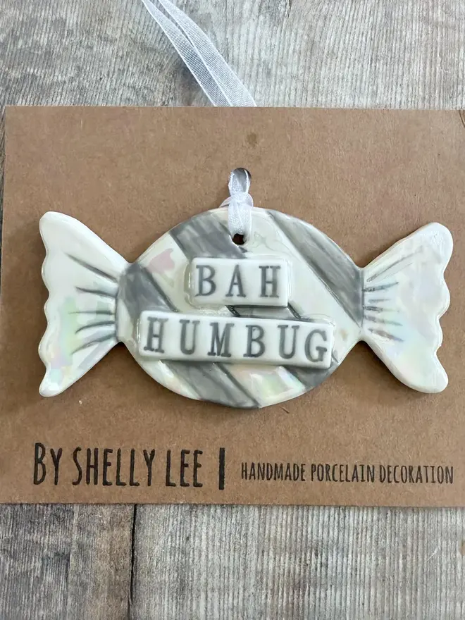 'Bah Humbug' Handmade Porcelain Sweet Christmas Decoration, decoration packaged above a table. 