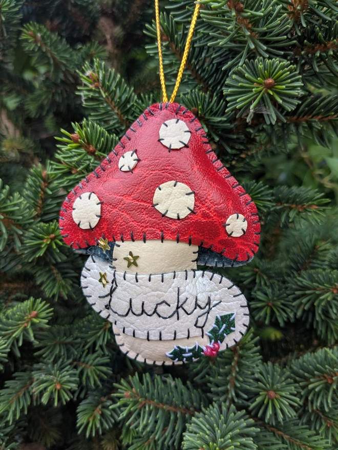 Hand stitched personalised toadstool Christmas decoration made from vegan-friendly faux leather, featuring a red mushroom cap, holly details and a personalised name banner.