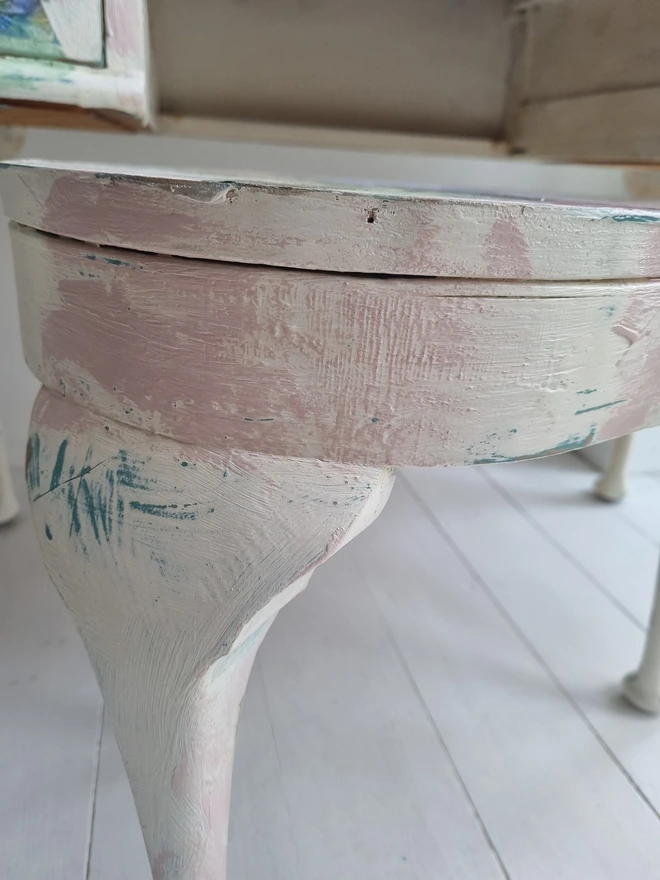 A painted dressing table in white and pale pink with large florals in blues and mauves and text in turquoise that reads 'turn your face to the sun'. The whole piece is distressed in the shabby chic style.