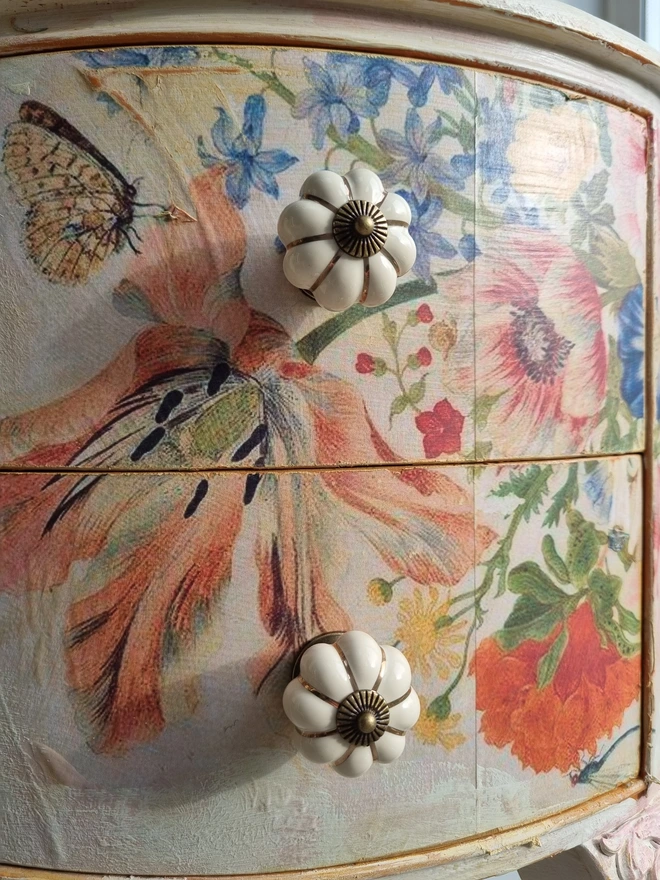 An antique kidney-shaped dressing table with chair and a trio of mirrors. Upcycled in cream and pale pink with decoupage florals in oranges and pinks. Text across the table read ‘flowers make me happy’ in the orange of the undercoat.