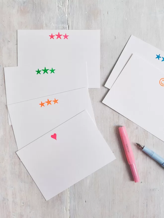 South London Letterpress, Neon Star Notecards seen on a wooden table with a heart card and a smiley face card.